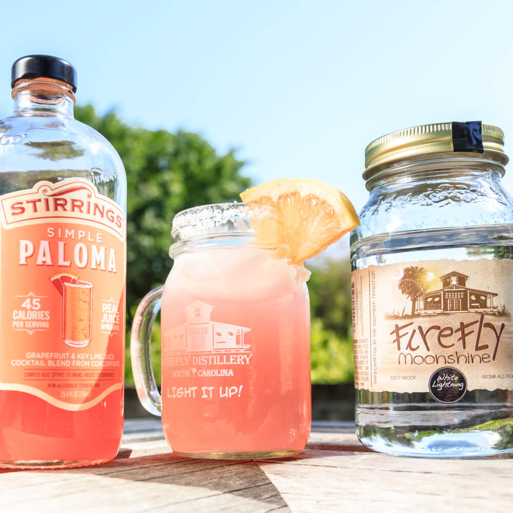 Paradise Paloma: 2 bottles and a mason jar with pink liquid and grapefruit slice garnish