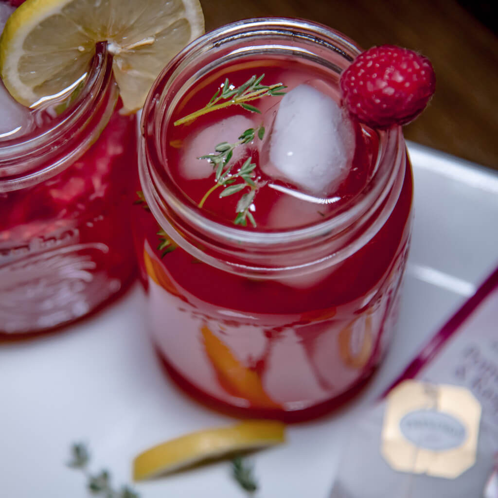 Mason jar with ice and cocktail, raspberry garnish