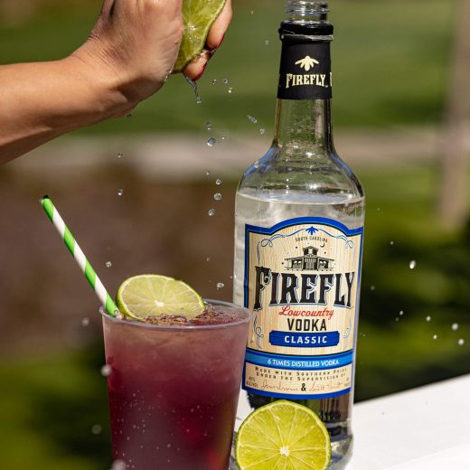Firefly Vodka bottle, hand squeezed Lime over beverage in glass